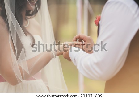 The groom wears his beautiful bride wedding ring