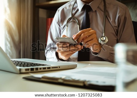 Medical technology concept. Doctor working with mobile phone and stethoscope and digital tablet laptop in modern office at hospital in morning light