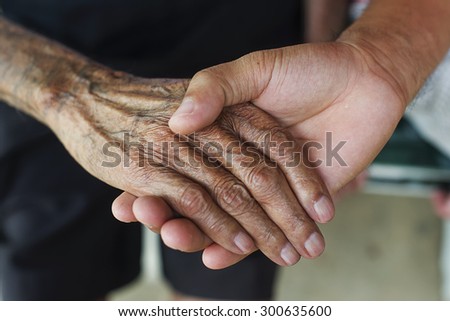 The young man holds the hand of the old man\'s hand.