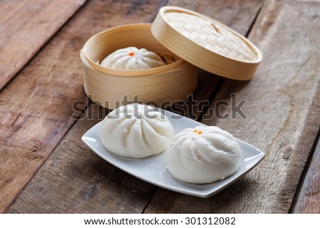 Chinese steamed bread in white dish on a wooden table.