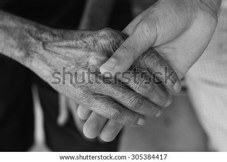 The young man holds the hand of the old man\'s hand. Black and White.