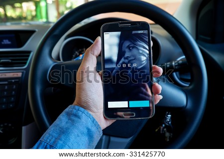 CHIANG MAI,THAILAND - OCT 26,2015 : A man hand holding Uber app showing on Samsung in the car,Uber is smartphone app-based transportation network.