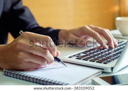 businessman hand working with new modern computer and writing on the notepad strategy diagram as concept morning light
