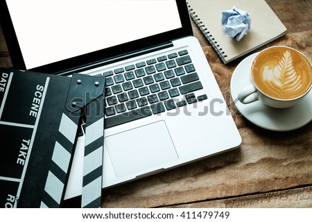 office stuff with Movie clapper laptop and coffee cup pen notepad on the wood table top view shot.dark effect