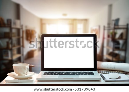 Workspace with blank screen coffee cup on a table in bright office room interior.
