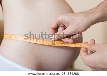 Happy parents measuring pregnant woman\'s bellyÃ?? Prenatal health care concept.