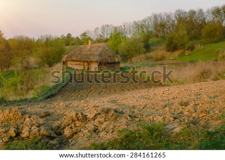 Agricultural land near old abandoned wooden house in Ukraine. Rural landscape in the morning. Low angle view on ploughed land plot in spring