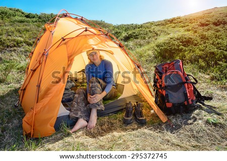 Young women in camping location with backpack. Mountain valley on a sunny morning