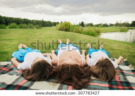 Family on picnic near the lake in the same clothes. Relaxing on the blanket. View from the head side