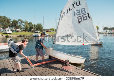 Kaunas, Lithuania - June 10, 2014: Lessons in Kaunas sailing school for children on Kaunas Sea. Two children launching small sailboat on water of the lake.