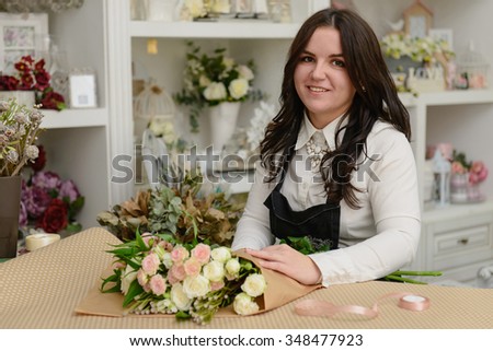 Portrait of smiling florist standing near the table wrapping the flowers in the shop