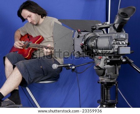 black high definition camcorder shot the guitarman in studio with blue background