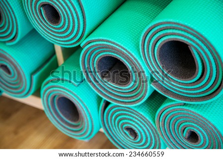 Yoga mats constricted, rolled-up on a shelf in the closet.