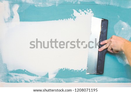 Hand with putty knife repair wall, Hand with a spatula, spatula with spackle paste structure, process of applying layer of putty trowel, working with spackling paste