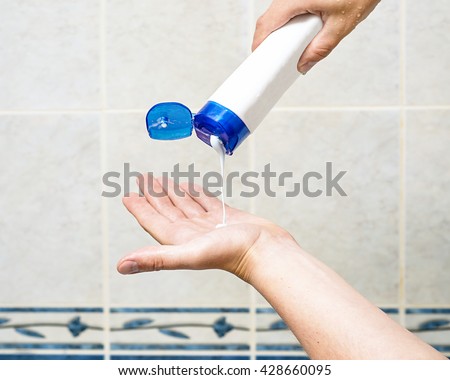 man is pouring shampoo on his hand, shower gel on hand, man hand holding bottle with shampoo and squeezing shampoo for hair from tube