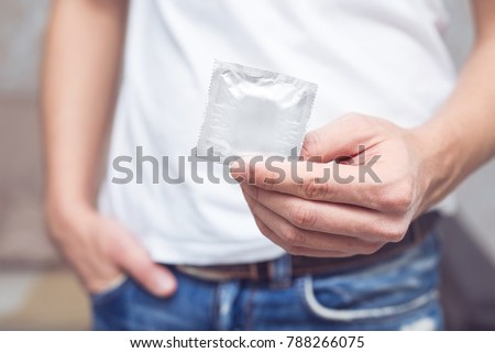 Young men\'s jeans back pocket to carry condoms on Valentine\'s holiday, sensual man holding condom foe use it to protect, man taking condom from jeans, guy giving condom, Safety sex concept