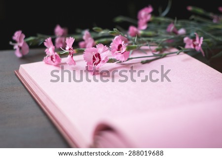 Opened vintage photo album with pink pages on wooden table, sweet william flowers, space for romantic text, selective focus