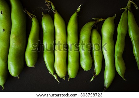 green bean pods in a row on black background