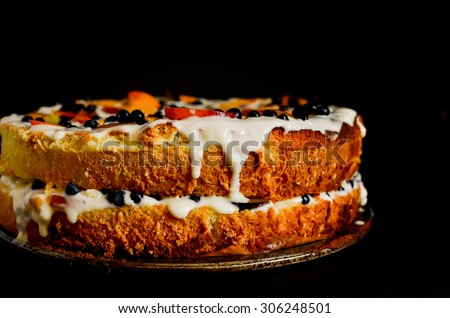 summer biscuit cake with cream blueberries peach slices and plum on black backgroung horizontal composition soft focus close up