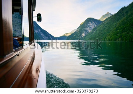 view from the boat window. Ferry is old and wooden. View on the Koningsee lake in Bavaria, Germany. Water and mountains on background
