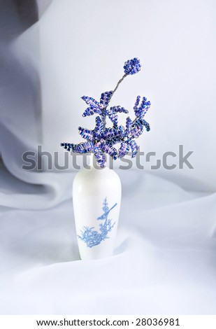 Tiny vase with a bead bouquet in it, still life.  On a light background
