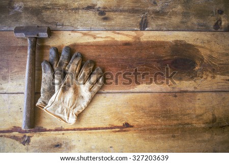 Worn work gloves with hammer on wooden work table