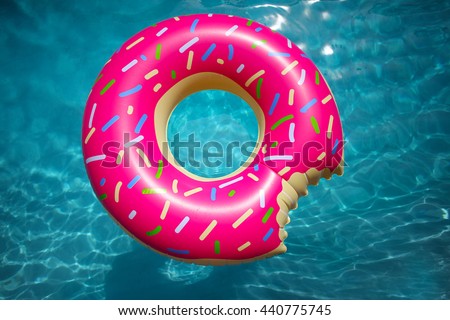 Hipster sprinkled donut float in sunny pool background straight down on bright clear pool water