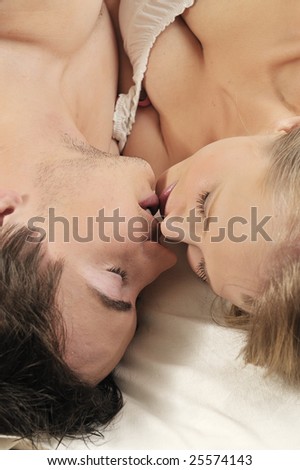 Young couple in love lying in the bed kissing