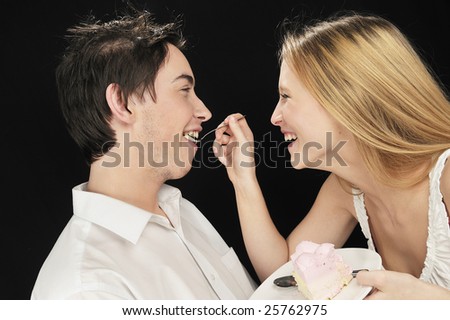 Young couple in love feeding each other with cake