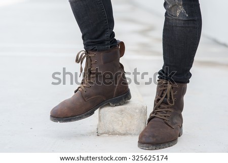 Men fashion legs in black jeans and brown leather boots on white