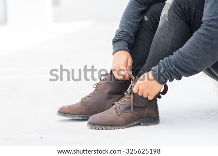 Men fashion legs in black jeans and brown leather boots on white