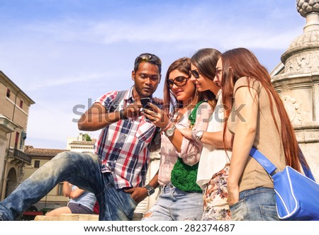 Group of happy students having fun with smartphone in old town center - Summer friendship concept with tourists watching map on smart phone at city tour - Best friends on sunny afternoon color tones