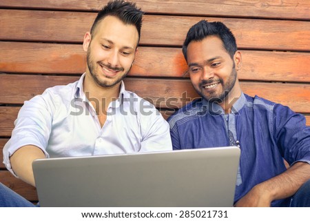 Happy couple guys using modern laptop computer - Smiling men models with pc device - Technology concept with best friends watching online news - Multiracial teenagers and friendship against racism