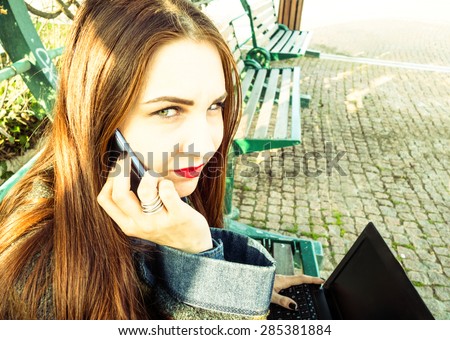 Young woman with mobile and laptop sitting in a park calling for help after being harassed - Green eyes model with angry expression - Concept of sadness and solitude caused by violence against women