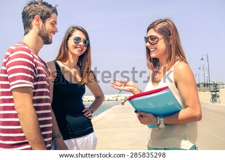 Business woman selling property to young cheerful couple for summer vacations -  Happy tourists on trip location talking with female broker - People concept of real estate sale in travel destination