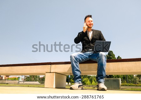 Young hipster business man sitting with laptop and mobile phone - Modern concept of technology wifi connection - Handsome businessman working outdoors with pc and smart phone connected by internet
