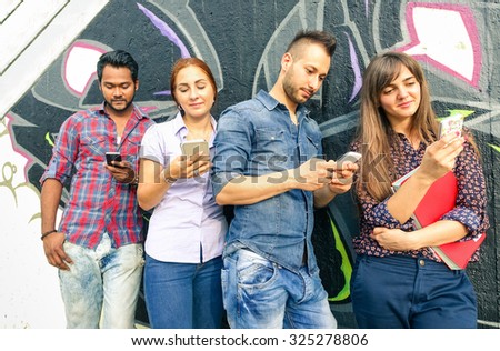 Group of friends with mobile sharing sms online - Multiracial students play with cell phone technology addicted - Young hipster people use smartphone - Concept of urban friendship - Graffiti modified