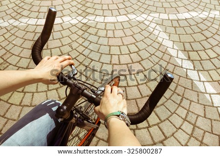 Woman riding  bicycle in central city square - Woman hands on modern sport bike -  Young girl cycling in urban street - Green concept of alternative transport preserving and saving environment matters