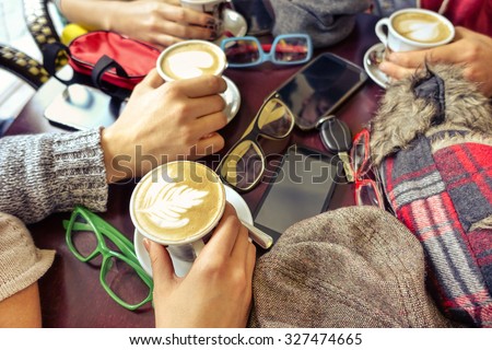 Hands holding capuccino cup - Group of friends having fun in cafe drinking decorated milk and coffee mug - Concept of friendly business meeting with trendy drinks and mobile phone focus on lowest cup