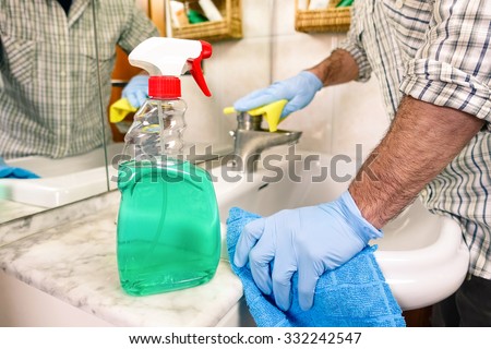 Single man cleaning bathroom - Male arms with blue gloves rubbing the sink tap in house washroom - Young man having fun with housework and sanitizing  - Concept of social change and new lifestyle