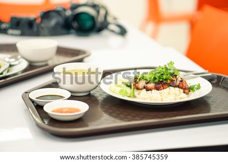 Thai food rice with pork chinese style at airport lounge in Bangkok - Asian fast food dish on table with blurred camera background as concept of travel around the world - Focus on the pork meat