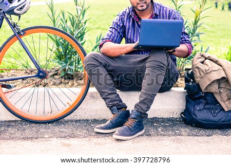 Indian man with laptop and sport bike sitting in city park - University asian student with pc and bicycle outdoor - Freelance young guy work with computer outside - Concept of modern green lifestyle