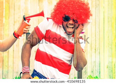 Afro american man fan of football have fun with bizarre look for international sport event - Black african male with funny wig is screaming deafened by unpleasant noise - Concept of health danger