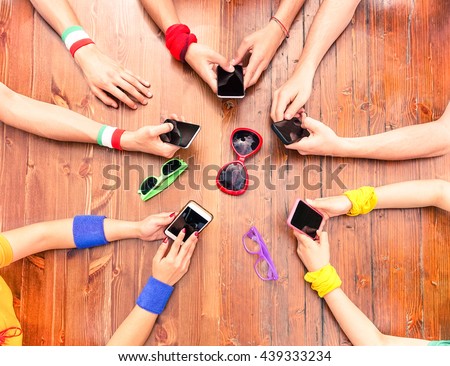 Many white hands using phone view from above - International people around wood table holding new mobile - Concept of modern technology addiction in everyday life - Focus on lower left telephone