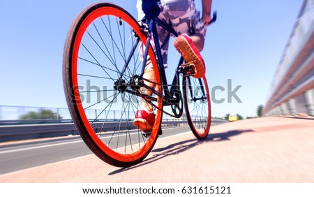 Man cycling on sport bike - Bicycle wheels and road perspective with cyclist riding  blue summer sky background - Concept of alternative transportation  environmental friendly  with radial zoom filter