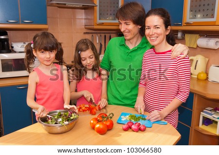 Family at home cooking salad. Happy smiling parents with kids cook healthy food together at kitchen
