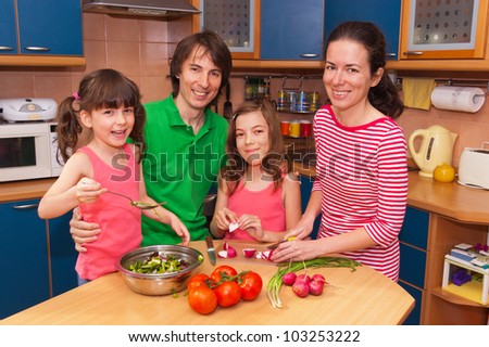Family cooking at home. Happy smiling parents with kids cook healthy food together at kitchen. Family preparing salad