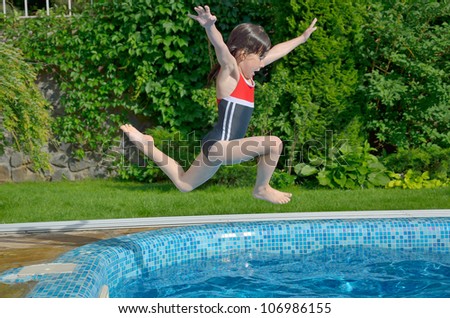 Happy active child jumps to swimming pool. Beautiful smiling girl having fun on summer vacation. Kids sport and holiday