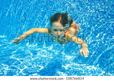 Happy smiling underwater child in swimming pool, beautiful girl swims and having fun. Kids sport on summer vacation. Active holiday