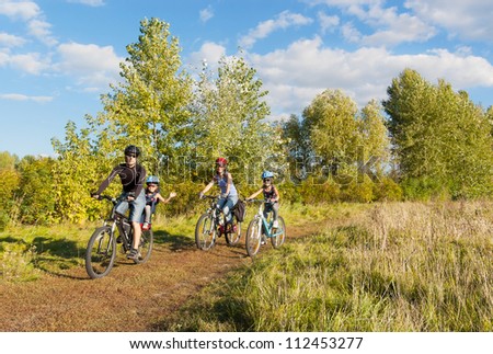 Active family on bikes cycling outdoors. Happy parents with two kids on bicycles. Sport and healthy lifestyle with children, family summer vacation